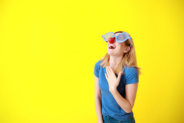 Fototapeta premium Funny woman with party decor for April Fools' Day on color background