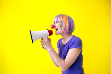 Naklejka premium Funny woman with megaphone on color background. April Fools' Day prank
