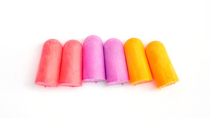 Yellow, violet and pink earplugs on a white background.