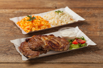 Grilled pork neck served on paper trays.