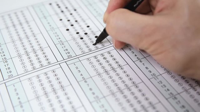 Man is filling OMR sheet handing with pen.