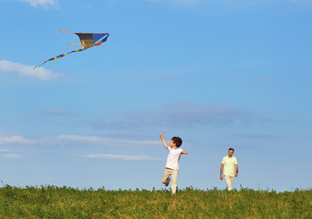 Father and son playing with a kite in nature.