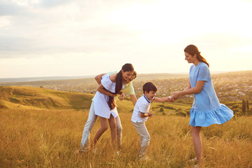 Happy family playing fun on the field at sunset.