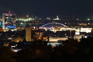 Fototapeta na wymiar Night view on the city. Red lights, buildings, bridge and factory.