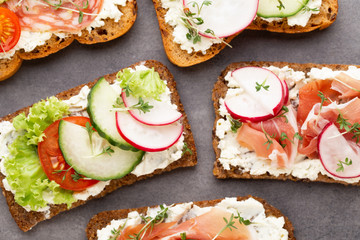 Sandwich with cereals bread and salami on dark marble background.