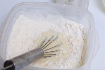 Cooking the pie with mascarpone cream. A whisk for mixing is in the container with the dough.