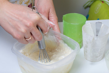 Cooking the pie with mascarpone cream. Woman kneads dough in container.