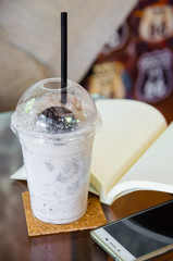 milk chocolate smoothie with open book and smartphone on glass table