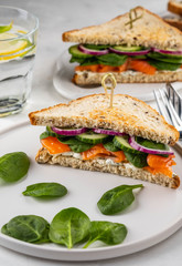 Sandwiches with cream cheese, salmon and spinach on a white backround.