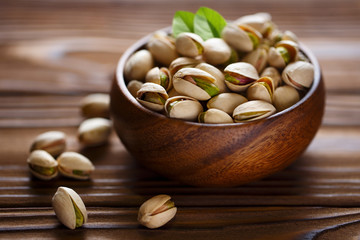 Close-up of delicious pistachios in a wooden bowl on a wooden table