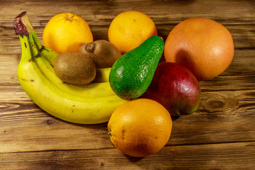 Assortment of tropical fruits on wooden table. Still life with bananas, mango, oranges, avocado, grapefruit and kiwi fruits