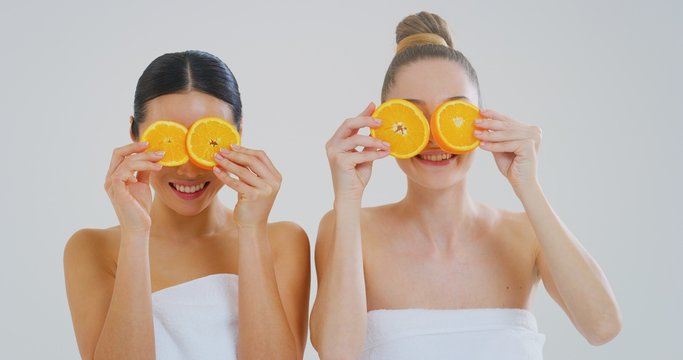 Portrait of beautiful young women of different ethnicities with perfect faces with eyes covered with kiwi slices smiling in camera isolated on a white background.