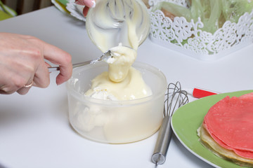 Cooking the pie with mascarpone cream. A woman prepares an impregnation of mascarpone for the cake. Adds condensed milk.