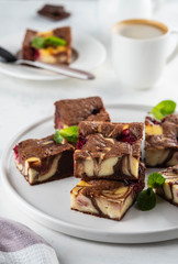 Cheesecake brownies with raspberry stacked on a white plate.