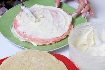 Cooking the pie with mascarpone cream. A woman lubricates the mascarpone and condensed milk cakes.
