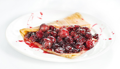 Thin delicious pancake with berry jam on white