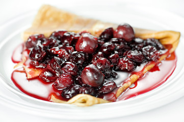 Thin delicious pancake with berry jam on white