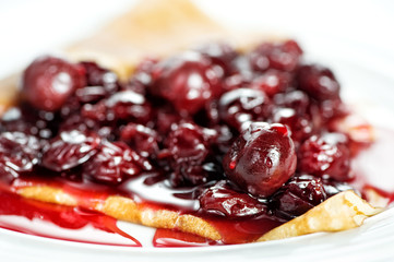 Thin delicious pancake with berry jam on white