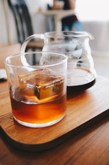 coffee drip in glass with cube ice on wooden plate