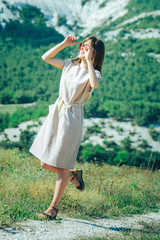 Obraz premium An attractive girl in sunglasses on a walk in a mountainous area enjoys a Sunny day and a good mood.