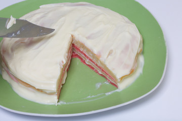 Cooking the pie with mascarpone cream. The finished cake, smeared with impregnation, lies on the plate. Color layers are visible.