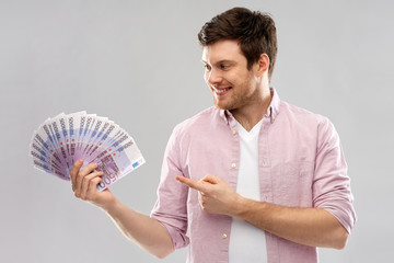 money, finance, business and people concept - smiling young man showing fan of five hundred euro...