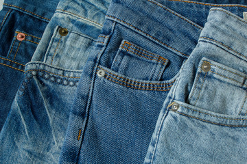 Fototapeta premium New denim pants clothes pile background. Stack of blue jeans different shadows