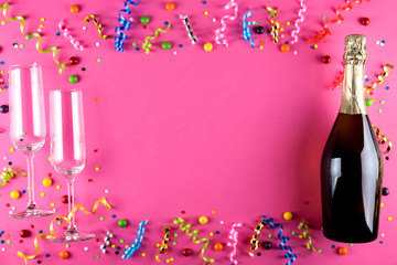 Bottle of champagne, flute glasses with confetti, streamers and other party attributes in flat lay...