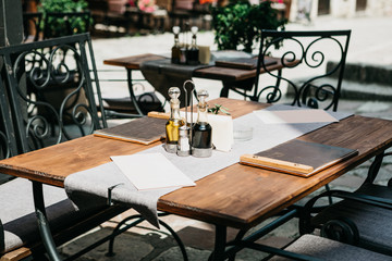 Traditional European cafe. On the table are the menu and there are sauces or butter. There are chairs nearby. Waiting for visitors.