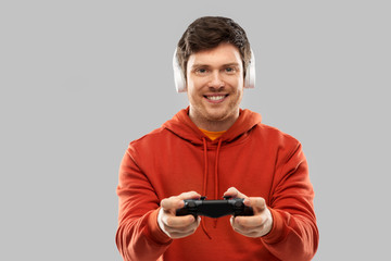 technology, gaming and people concept - young man or gamer in headphones with gamepad playing video game © Syda Productions