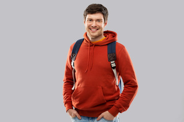 education, travel and people concept - young man or student with school bag or backpack over grey background