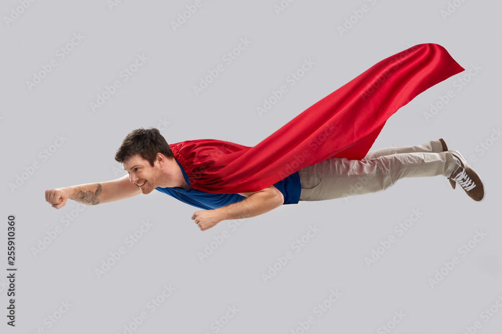 Canvas Prints super power and people concept - happy young man in red superhero cape flying in air over grey background