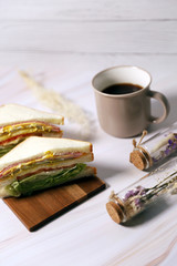 cup of coffee and sandwich on wooden table