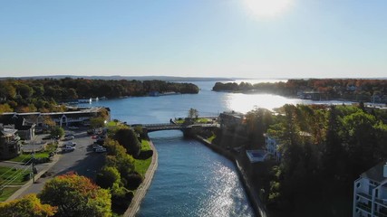 Warm Fall Day Charlevoix Northern Michigan sun bursting through Trees bridge and river Lake Michigan.