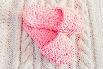 Pink women's Slippers on a white knitted blanket.