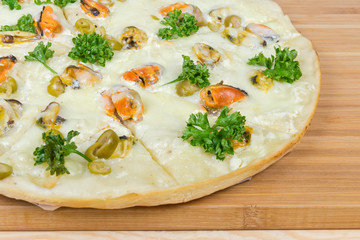 Part of cooked pizza with mussels on bamboo cutting board