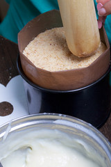 Cooking a cake of biscuit crumbs and milk jelly. On the surface of the table are the ingredients and cooking utensils.