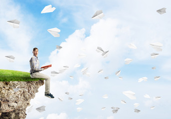 Handsome student guy with book in hands preparing for exam