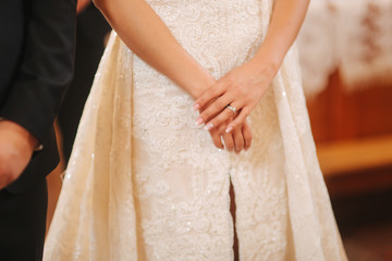 Hands of bride in the church. Wedding dress