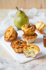 Delicious home made breakfast: sweet cupcakes with pears. Served with honey in a glass jar and walnuts on a white board