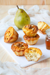 Delicious homemade breakfast: sweet cupcakes with pears. Served with honey in a glass jar and walnuts on a white board.