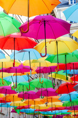 Fototapeta na wymiar A place in the center of Paris with colorful umbrellas instead of ceiling. Yellow red pink blue green orange. Sunlight coming from the top. Wind is blowing