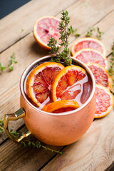 Red oranges cocktail in copper mug (variation of Moscow mule) on the wooden background. Selective focus. Shallow depth of field.