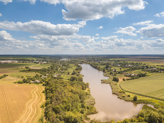 Fototapeta premium Panoramic view with farmfields, countries, wide river on a background blue cloudy sky in a summer day.