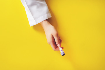 Laboratory assistant holding test tube with blood sample on yellow background