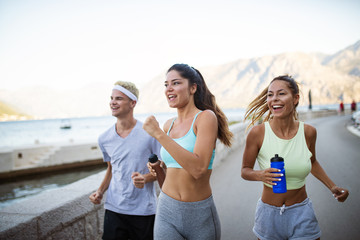 Group of young people friends running outdoors at seaside