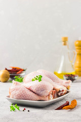 Raw chicken legs, pepper, olive oil on concrete background. Selective focus, space for text.