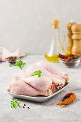 Raw chicken legs, pepper, olive oil on concrete background. Selective focus, space for text.