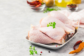 Raw chicken legs,spices and olive oil on concrete background. Top view, space for text.