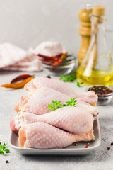 Raw chicken legs,spices and olive oil on concrete background. Top view, space for text.